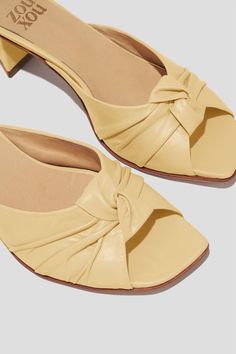 The Greta is a boudoir slipper-inspired mule that captures a playful mix of daytime sensibility & evening refinement. Whether you’re wearing the Greta for daytime play or after-dark doings, you will feel both comfortable and well-turned-out, thanks to a low, triangular heel and a pretty pleated-knot detail at the toe. Style Greta back to loose, casual pants for a breezy date look, or wear them with a cocktail dress to the next wedding on your calendar. Kidskin leather upper, vegetable tanned leather lining, leather outsole. Heel height: 1 ¾ inches (45 mm) Handmade in Argentina Elegant Beige Mules For Spring, Chic Beige Low Heel Mules, Elegant Flat Heel Mules For Spring, Elegant Spring Flat Heel Mules, Summer Formal Beige Mules, Beige Formal Mules For Summer, Chic Flat Heel Mules With Wrapped Heel, Chic Mules With Wrapped Flat Heel, Elegant Flat Heel Summer Mules