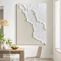 a dining room table with chairs and a large painting on the wall above it that has white paint