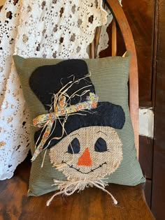 a pillow with a scarecrow on it sitting on a chair next to a lace doily