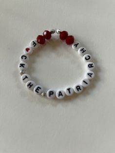 a white bracelet with red beads and letters on it