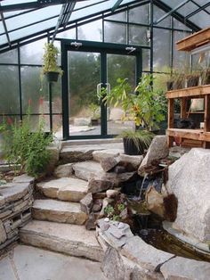 an outdoor garden with rocks and plants in the center, surrounded by glass walls that allow natural light