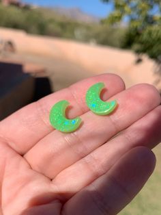 Each pair of sparkly green glow moon stud earrings are handmade to order, therefore no two pairs are identical! Every resin jewelry piece in my shop is slightly unique and one of a kind. However, I try to get as close to the listing photos as possible :) Hypoallergenic stainless steel stud earrings. Moons are 13mm x 11mm are made with epoxy resin, neon green glow pigment & iridescent light green glitter ✨  Glow in the dark & UV blacklight reactive!! Perfect for parties, raves, festivals, etc! Co Cute Green Jewelry For Party, Handmade Magical Style Green Jewelry, Handmade Magical Green Jewelry, Cute Handmade Green Jewelry, Whimsical Green Round Jewelry, Glow In The Dark Clay Earrings, Glow In The Dark Jewelry, Glowing Earrings, Green Luminous Round Jewelry