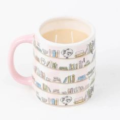 a pink and white coffee mug with books on the inside is filled with tea in front of a white background