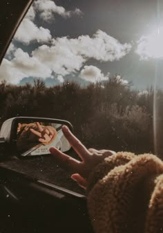 a person's hand on the dashboard of a car as they look at clouds