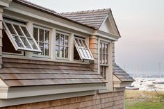 there are many windows on the side of this house and boats in the water behind them