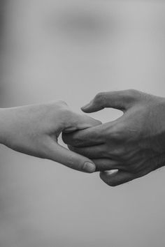 black and white photograph of two hands reaching for each other's hand in the air