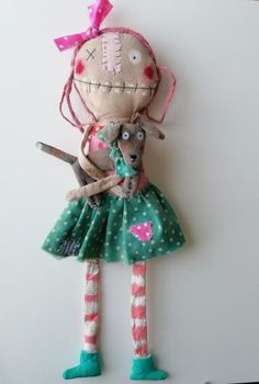 a stuffed doll holding a small dog wearing a green dress and pink headbands