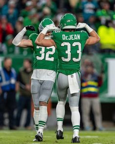 two football players standing next to each other on a field with fans in the background