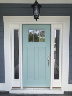 a blue front door with two sidelights and a light fixture on the outside wall