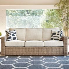 a living room scene with focus on the couch and rugs in front of the window