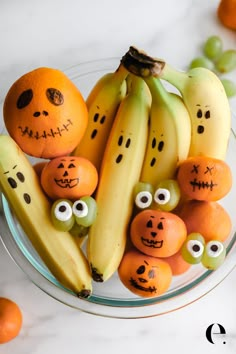 a bowl filled with oranges and bananas decorated like jack - o'- lanterns