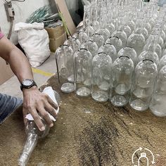 there is a lot of empty wine bottles on the table and one person has their hand in an empty glass bottle