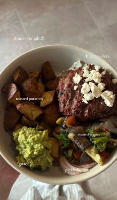 a white bowl filled with meat, potatoes and veggies on top of a table