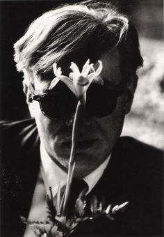 a man wearing sunglasses and holding a flower