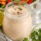 a glass jar filled with dressing next to a salad