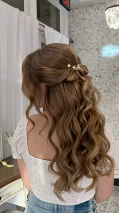 a woman with long curly hair wearing a white top