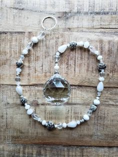 a white beaded bracelet with a crystal stone and silver beads on top of it