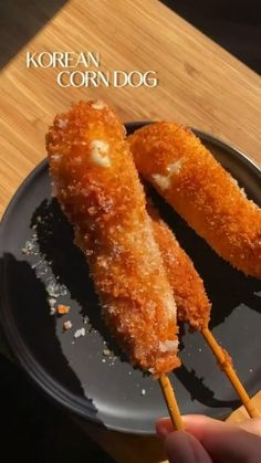 two fried food items on a black plate with chopsticks in the foreground