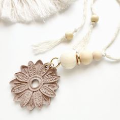 a tasseled necklace with a flower on it and two beads hanging from the end