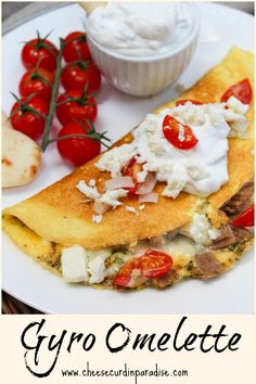 a white plate topped with an omelette covered in cheese and tomatoes next to a bowl of yogurt