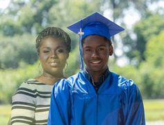 two young people in graduation gowns posing for the camera