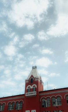 a large red building with a clock on it's side and a sky background