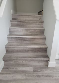 some stairs in a house with white walls and wood flooring on the bottom level