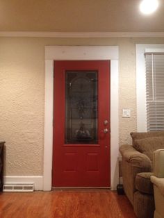 a living room with a red door and white walls