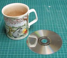 a coffee cup with a cd in front of it on a table next to a blue mat