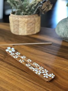 a wooden stick with white flowers on it sitting on a table next to a potted plant