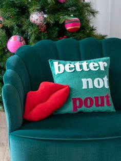 a green chair with a red pillow sitting on top of it next to a christmas tree