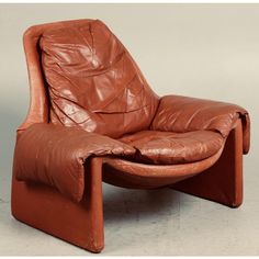 a brown leather reclining chair sitting on top of a white floor next to a wall