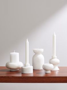 white candles are arranged on a wooden table