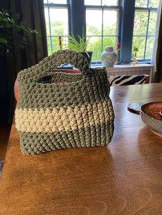 a bag sitting on top of a wooden table next to a bowl and potted plant