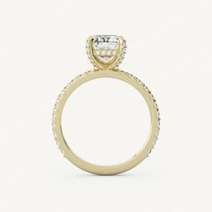 a yellow gold engagement ring with an oval cut diamond on the center and pave set shoulders