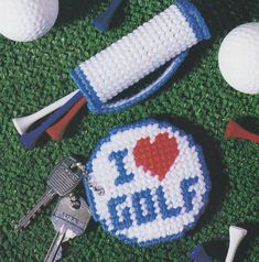 crocheted golf balls, tees, and keys on the ground with i love golf written on it