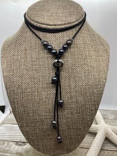 Boutique and Chic Leather and Freshwater Peacock Pearl Necklace. This necklace was hand knotted and created on a beautiful dyed noire black leather.  This leather is a 2mm cord that is soft and supple. The necklace will go with any coastal or boho clothing and it is modern and trendy to wear with business casual as well as a simple tee and jeans. It would also look great with any western style of clothing. The leather has been barrel knotted. As with all leathers, there is some distressing and t Bohemian Black Hand Knotted Jewelry, Black Handmade Adjustable Lariat Necklace, Black Leather Jewelry With Adjustable Cord, Black Bohemian Lariat Necklace, Black Bohemian Necklace With Sliding Knot, Bohemian Black Leather Necklace, Bohemian Black Jewelry With Sliding Knot, Black Hand Knotted Adjustable Necklace, Adjustable Black Hand Knotted Necklace