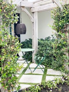 an outdoor patio with chairs and table surrounded by greenery