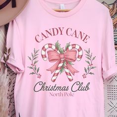 Join the holiday fun with our Candy Cane Christmas Club Tee! This cute Comfort Colors garment-dyed T-shirt brings coquette charm to your festive wardrobe. Perfect as an Christmas gift, it's cozy, stylish, and ideal for spreading holiday cheer. Add a playful touch to your holiday season with this trendy, festive tee! Size up for an oversized fit. Comfort Colors introduces the "Comfort Colors 1717" garment-dyed t-shirt; a fully customizable tee made 100% with ring-spun cotton. The soft-washed, garment-dyed fabric brings extra coziness to your wardrobe while the relaxed fit makes it an excellent daily choice. The double-needle stitching throughout the tee makes it highly durable while the lack of side-seams helps the shirt retain its tubular shape. Discover all 58 colors in our Comfort Colors Christmas T Shirt, Christmas Tops, Christmas Candy Cane, Holiday Shirts, Christmas Tshirts, Dye T Shirt, Candy Cane, Holiday Fun, Comfort Colors