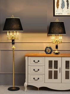 two lamps sitting on top of a table next to a cabinet with drawers and drawers