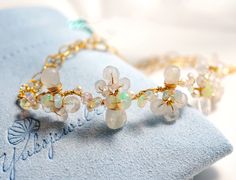 "The bangle is designed to represent lovely white flowers blooming on a vine.  Perfect for boho casual wedding or any of your special occasions.   ●  Material   14K gold filled ●  Gemstone   Rainbow moonstone and Fresh water pearl, Ethiopian Opal ●  Size  Flower vine  3.5\" (9cm) in length ●  Chain Patterned flat cable chain ●  Closure   Lobster claw ●  Come in a pouch and gift box ● Made to Order Processing time is 5 - 10 business days before shipping. If you need item(s) to ship within a tight Wedding Bangle Bracelets With Natural Stones, Wedding Bangle Bracelet With Natural Stones, Wire Wrapped Bangle Jewelry For Wedding, Gold Bracelet With Natural Stones For Wedding, Delicate Gemstone Bracelets For Wedding, Bohemian Gemstone Bracelets For Wedding, White Wire Wrapped Bracelets For Wedding, Bohemian Wedding Bracelets With Gemstones, White Wire Wrapped Wedding Bracelets