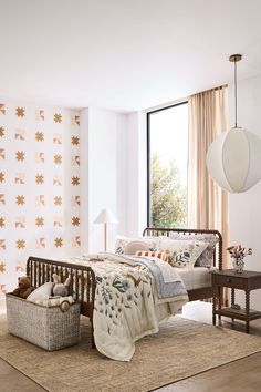 a bed room with a neatly made bed next to a window and a basket on the floor