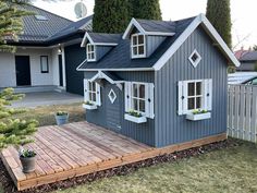 a blue house with white windows and shutters on the front, surrounded by grass