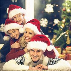 a family wearing christmas hats laying on the floor in front of a christmas tree with presents