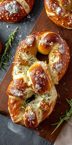 some breads with cheese and herbs on a wooden board next to other breads