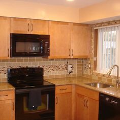 a kitchen with wooden cabinets, black appliances and brown tile backsplashing on the walls