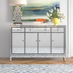 a living room with a large painting on the wall and a silver console table in front of it