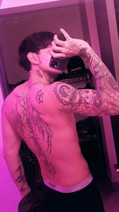 a man with tattoos taking a selfie in the mirror