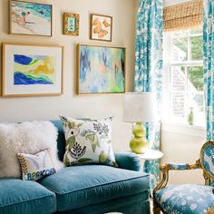 a living room filled with blue couches and pictures on the wall above them,