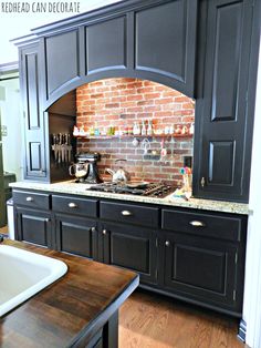 a kitchen with black cabinets and a brick oven in the center, along with a white sink